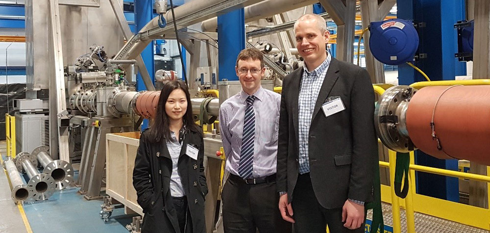 Research scientist Han Deng and Senior research scientist Sigurd W. Løvseth of SINTEF with Technical director Edward Jukes of KROHNE Ltd (middle) in front of the calibration facility. During calibration, tonnes of water are filled in the tank in the background. After a given time-period, the tank is weighed and the result compared with the reading of the flow meter under test.