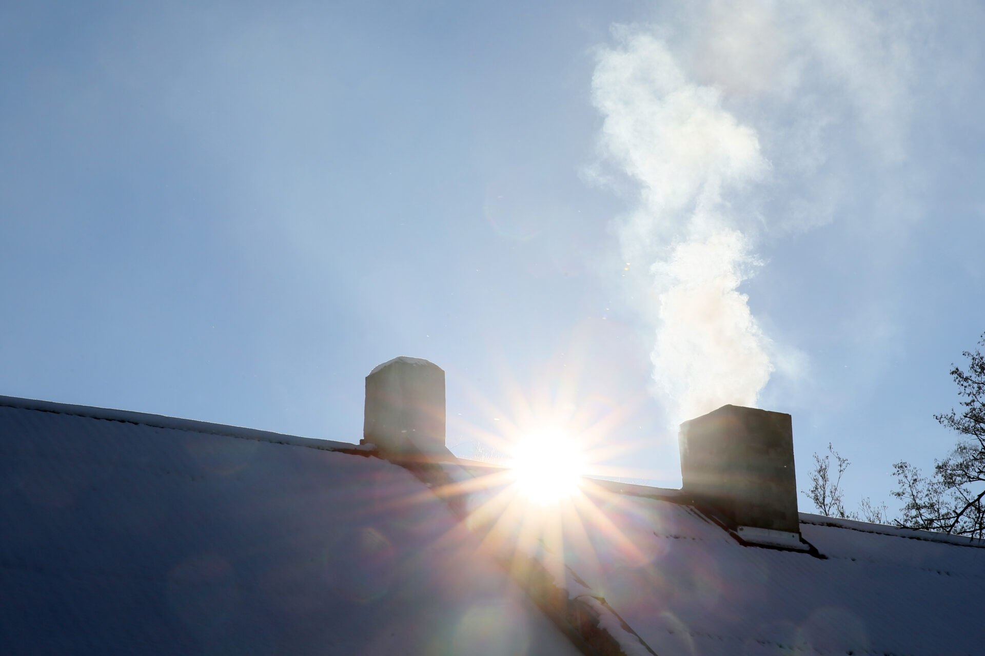 House with chimney and smoke. Sun in background.