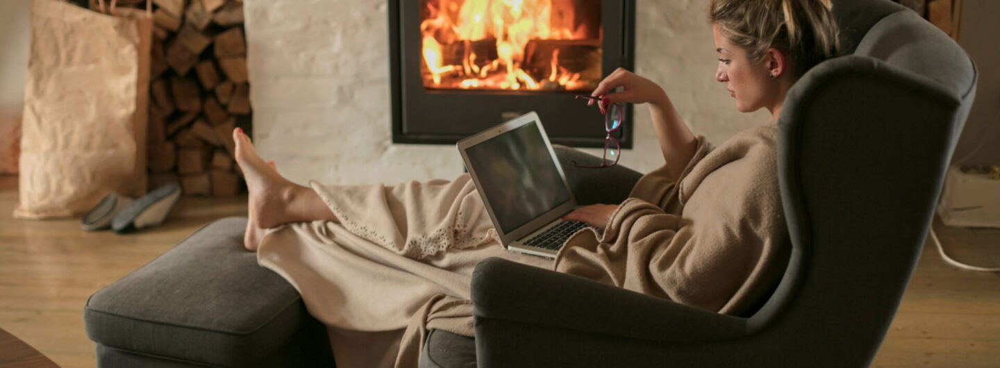 Woman working from home, with fireplace in the background