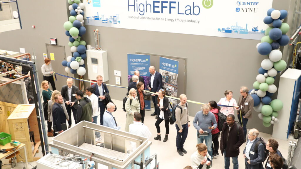 Official opening of HighEFFLab. Picture taken from above, showing banner, people people eating cake and lab equipment.