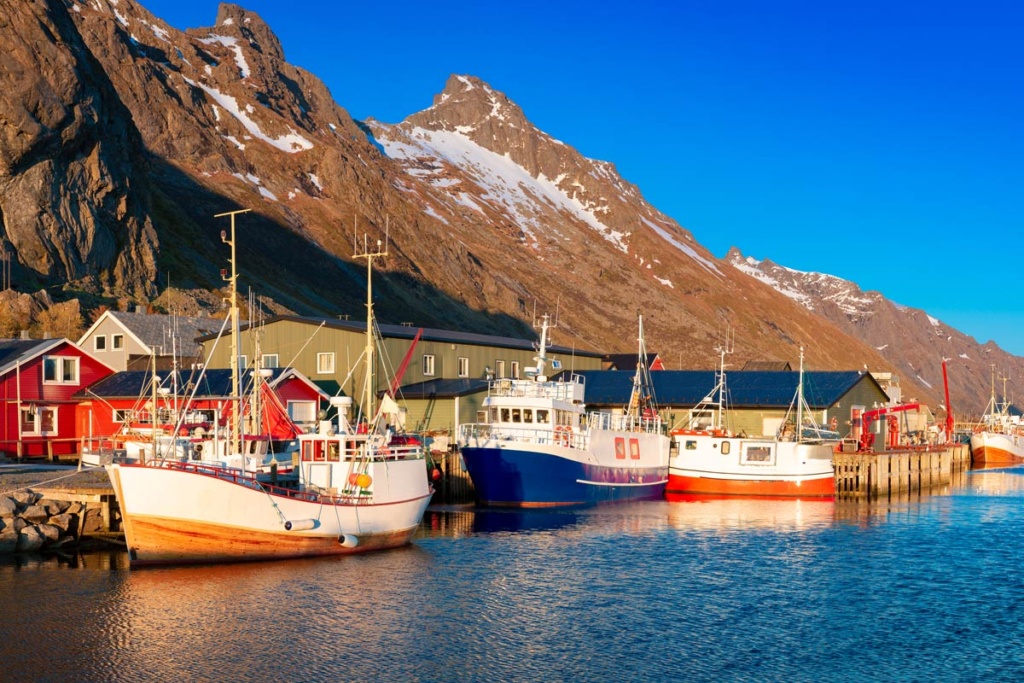 En idyllisk fiskerihavn i Nord-Norge med tradisjonelle fiskebåter som ligger fortøyd langs brygga.