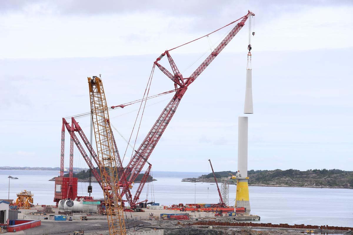 A very large crane is assembling the tower of a floating offshore wind turbine in Gulen, Norway.