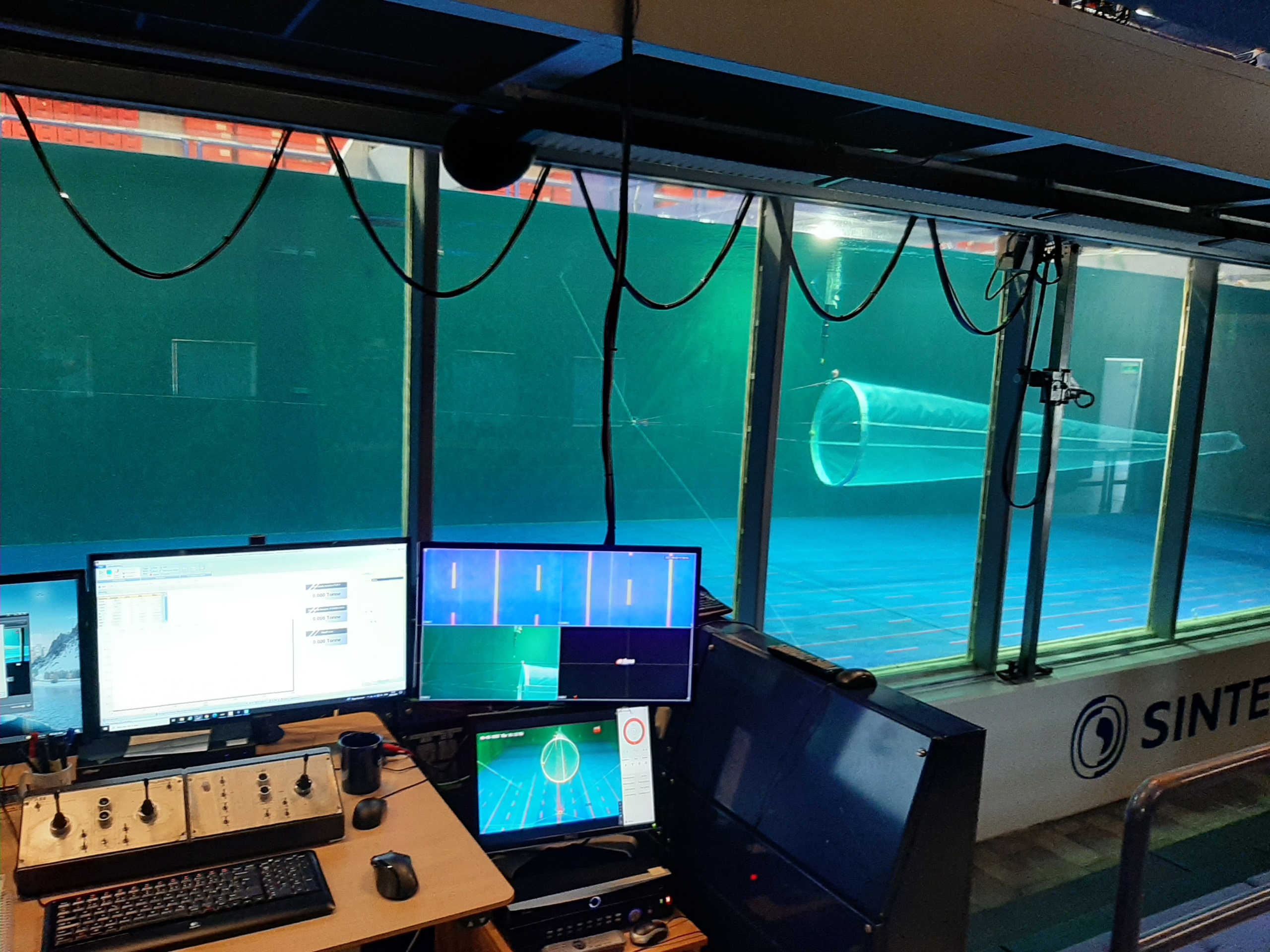 Computerscreens in front of a testing tank with a trawl net.