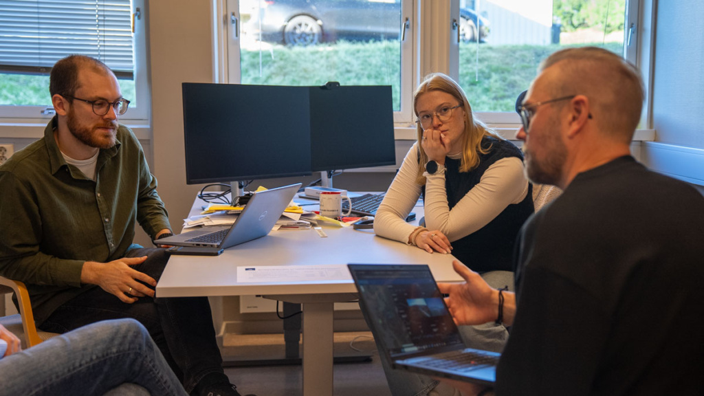 tre personer sitter rundt et bord