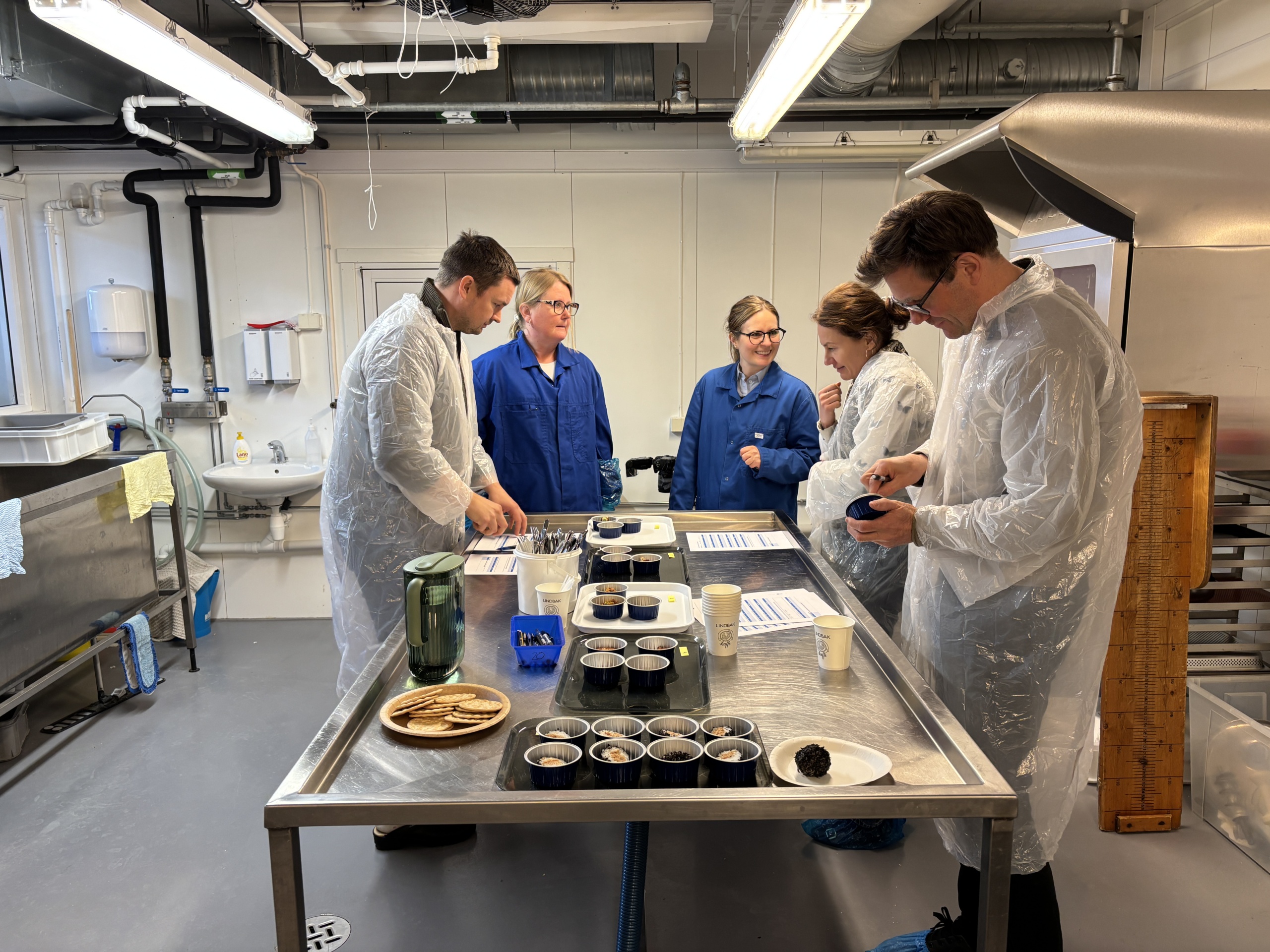 People tasting new food around a table in the kitchen laboratory.